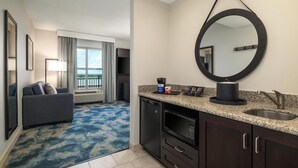 Une chambre d’hôtel dotée d’un coin salon, d’une kitchenette et d’un grand miroir.