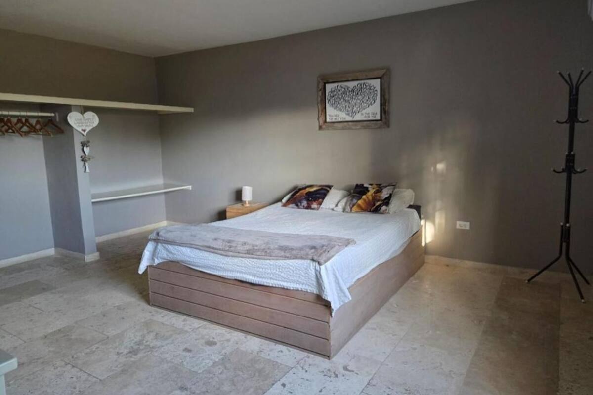 Une chambre à coucher comprenant un lit, une table de chevet, une étagère murale et un porte-manteau.
