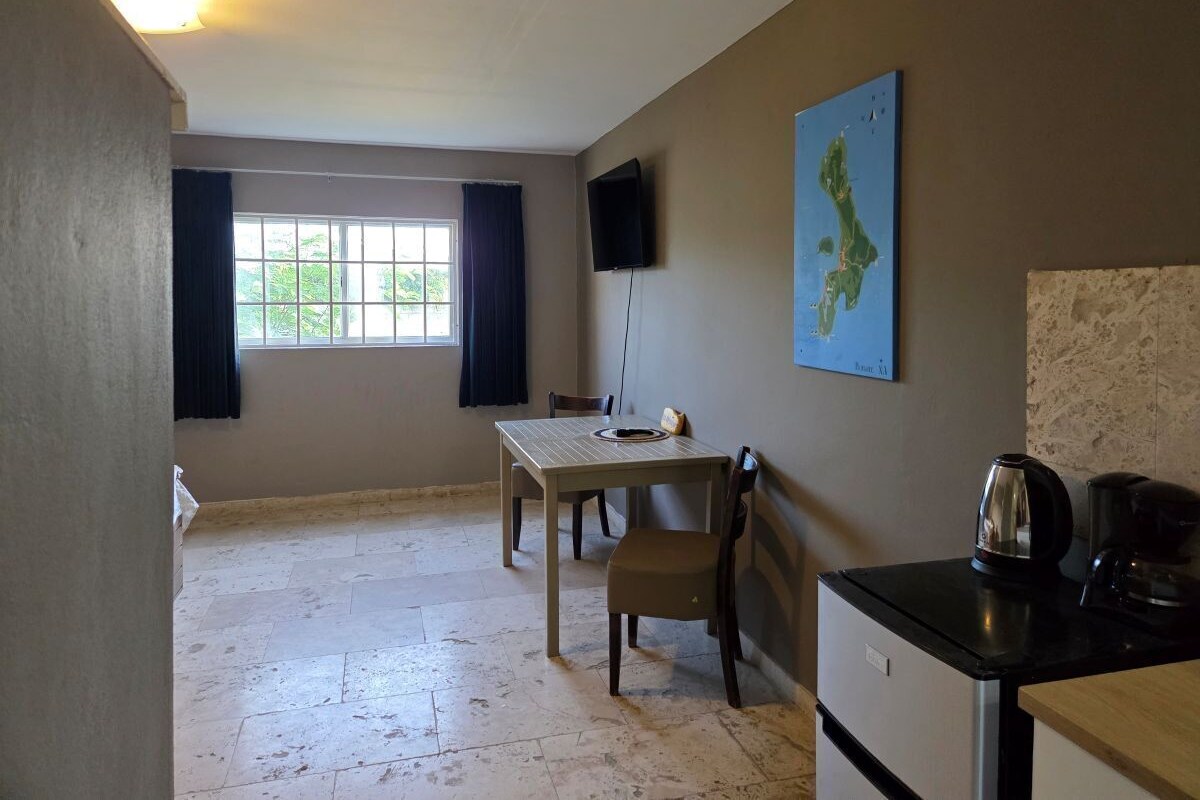 A room with a table, chairs, a television, a map, a kettle, and a coffee maker.