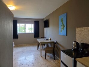 A room with a table, chairs, a television, a map, a kettle, and a coffee maker. - The Lodge Bonaire (Kralendijk)