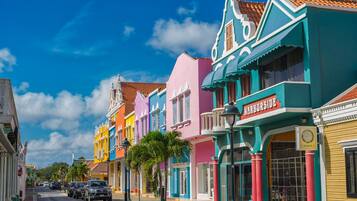 A colorful street with buildings, parked cars, and a clear blue sky.