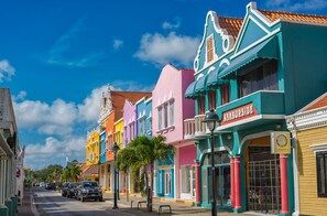 A colorful street with buildings, parked cars, and a clear blue sky. - The Lodge Bonaire (Kralendijk)