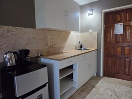 Una cocina compacta con encimera, fregadero y cafetera.