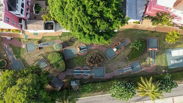 Vista aérea de un parque con varios espacios verdes, senderos y un gran árbol central.