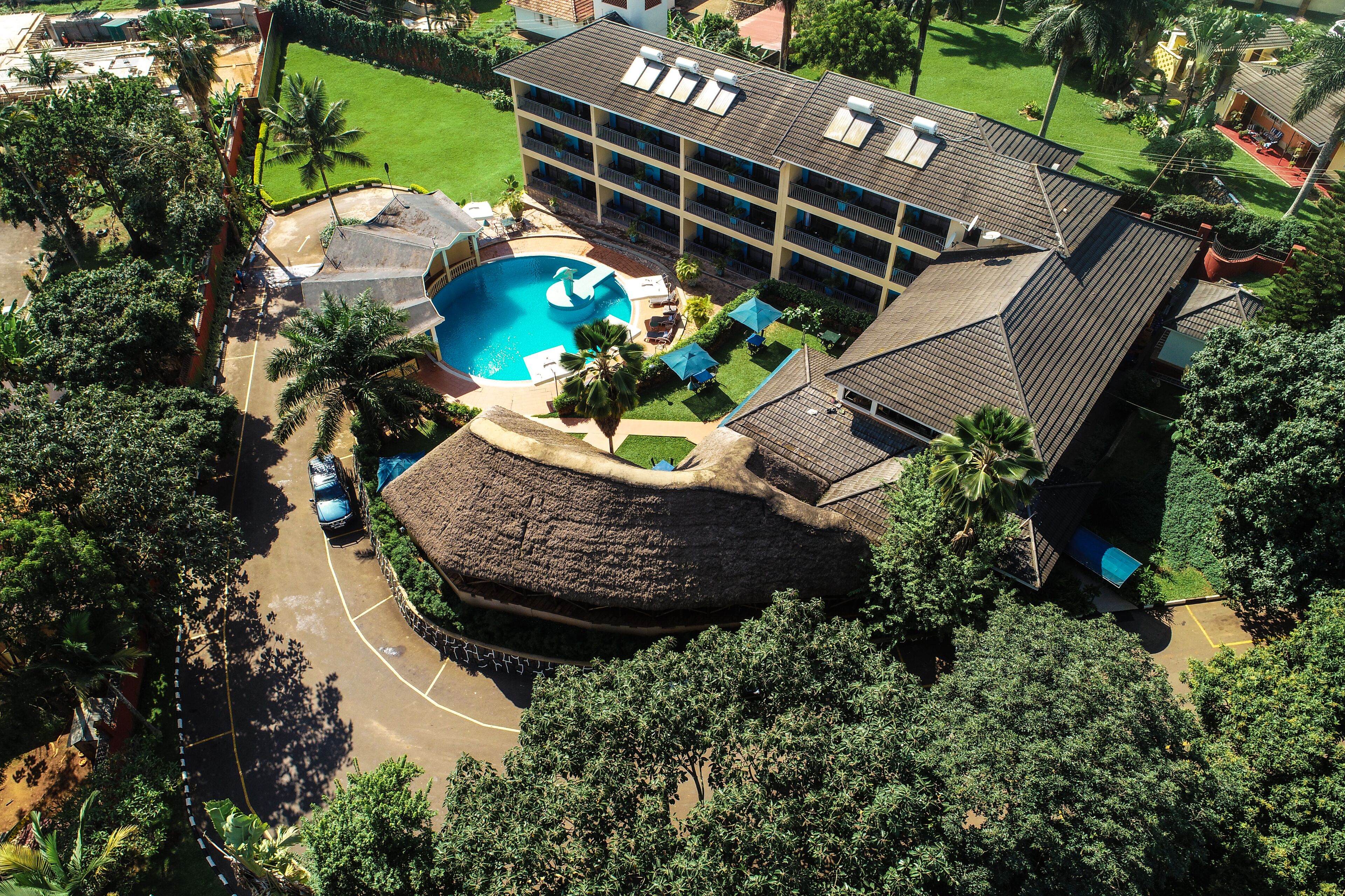 An aerial view of a hotel with a swimming pool, multiple balconies, and lush greenery.
