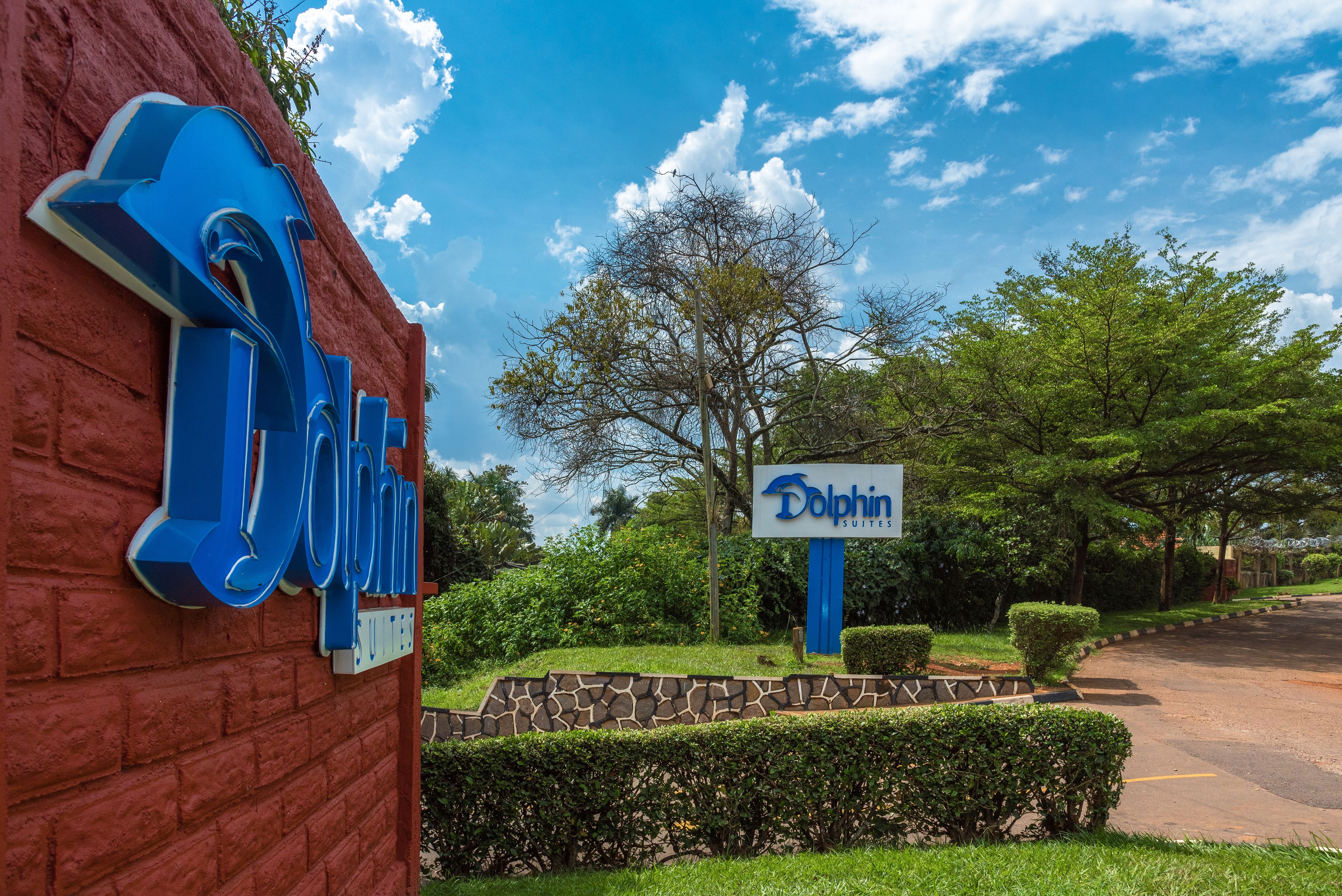 A hotel sign with the name 'Dolphin Suites' and a large blue 'D' on a red brick wall.