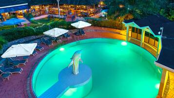 Relax by the pool surrounded by lush greenery and lounge chairs.