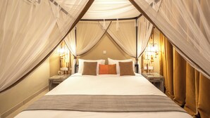 A tent-style bedroom with a bed, pillows, and bedside lamps. - Dolphin Suites (Kampala)