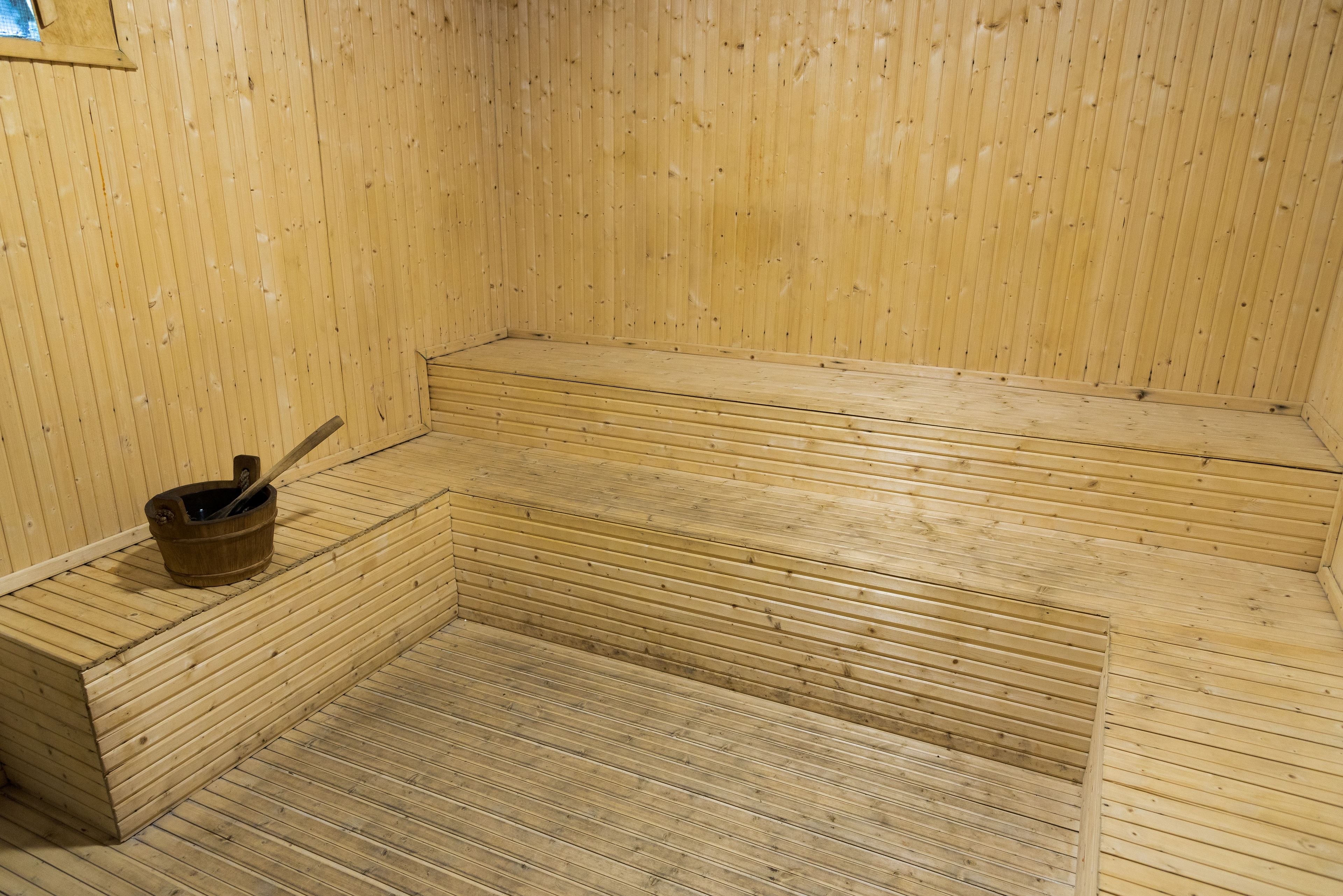 Una sauna con panche di legno e un catino di legno.