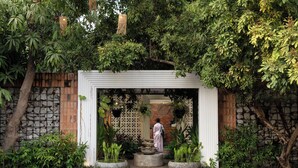 A garden entrance with a white archway, stone walls, and various plants. - Home Indochine D'angkor (Siem Reap)