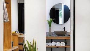 A bathroom with a wooden vanity, a round mirror, a potted plant, a sink, and neatly rolled towels. - Home Indochine D'angkor (Siem Reap)