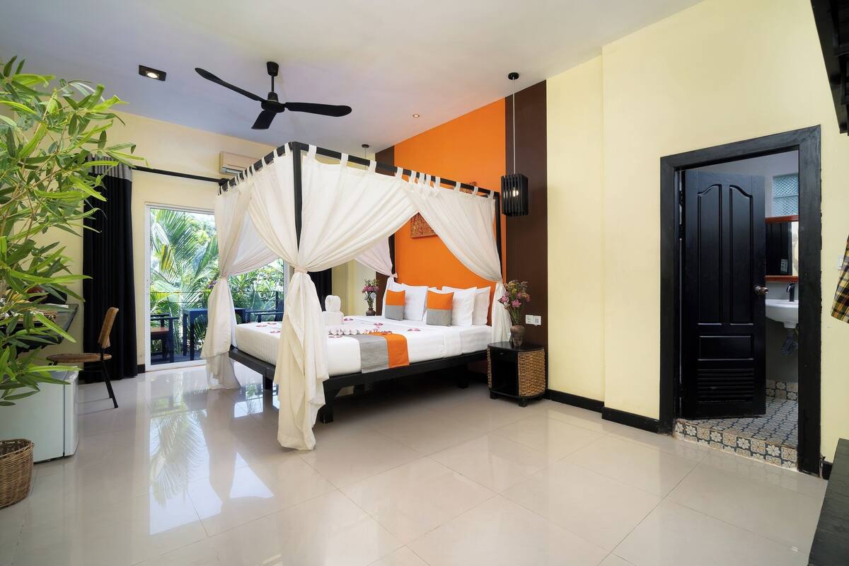 Un dormitorio moderno con cama con dosel, ventilador de techo y vistas al exterior.