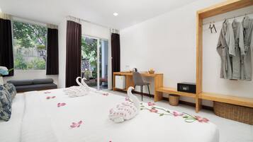 Ein Hotelzimmer mit einem Bett, einem Schreibtisch, einem Stuhl, einem Kleiderschrank und Blick auf Grünflächen.