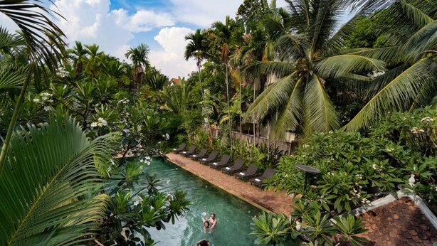 A pool surrounded by lush tropical vegetation and palm trees. - Home Indochine D'angkor (Siem Reap)