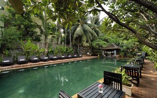 Una piscina al aire libre, sombrillas, sillones reclinables de piscina