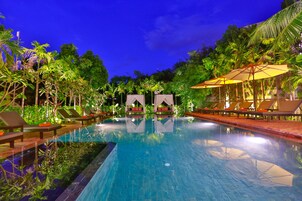 Una piscina al aire libre, sombrillas, sillones reclinables de piscina