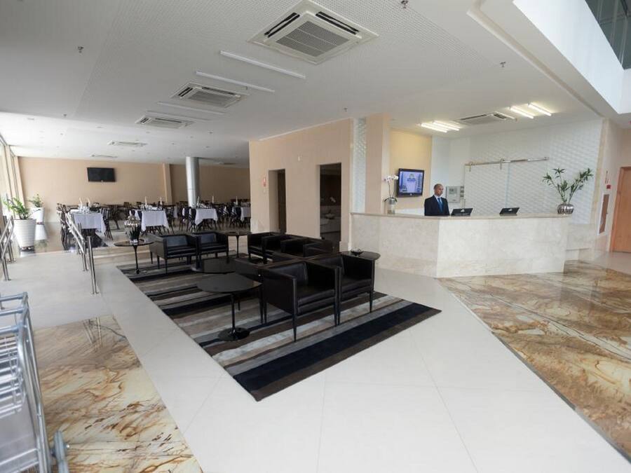 A modern hotel lobby with a reception desk, seating area, and a large window.