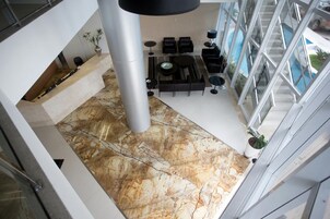 Um interior moderno com piso de mármore, móveis pretos e grandes janelas.
