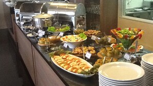 A buffet with various dishes and a grill station. - Days Inn Linhares (Linhares)