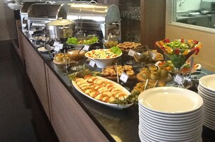 Buffet com diversos pratos e uma estação de grelhados.