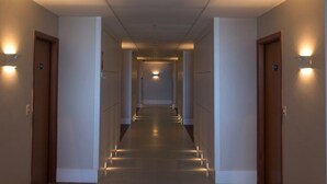 A long, narrow hallway with doors on both sides, illuminated by wall-mounted lights. - Days Inn Linhares (Linhares)