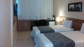 A hotel room with two beds, a desk, a TV, and a window with curtains. - Days Inn Linhares (Linhares)