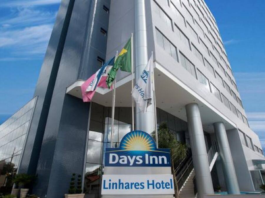 A modern hotel building with a prominent Days Inn sign and a Linhares Hotel sign.