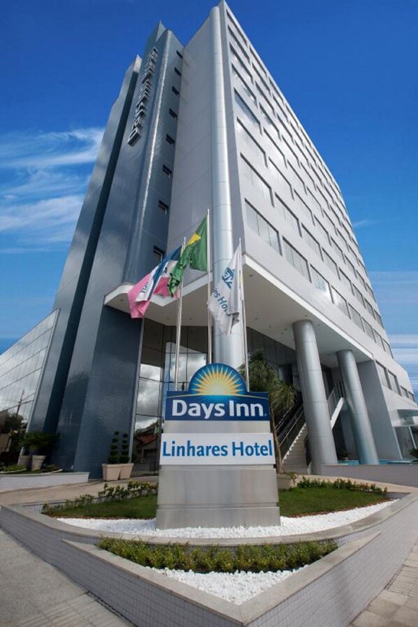 A modern hotel building with a prominent Days Inn sign and a Linhares Hotel sign.