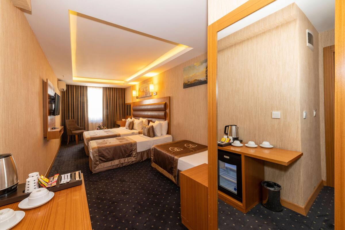 Ein Hotelzimmer mit zwei Betten, einem Schreibtisch, einer Kaffeemaschine und einem Fernseher.