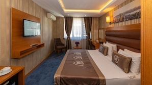 A hotel room with a bed, a TV, a desk, a chair, and a window with curtains. - Regno Hotel (Istanbul)