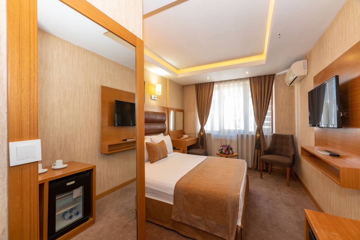 Ein Hotelzimmer mit Bett, Fernseher, Schreibtisch, Stuhl und Minibar.