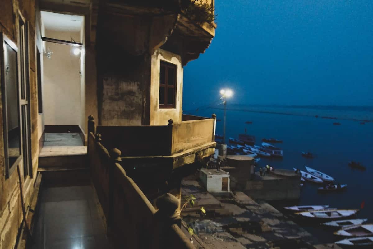 Vista nocturna de un edificio frente al agua, con un balcón que da a un muelle con barcos.