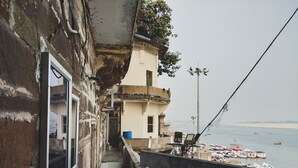 A balcony with a view of the sea and boats. There is a building with a balcony and a window. - Palace on steps (Varanasi)