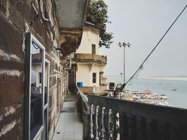 A balcony with a view of the sea and boats. There is a building with a balcony and a window. - Palace on steps (Varanasi)