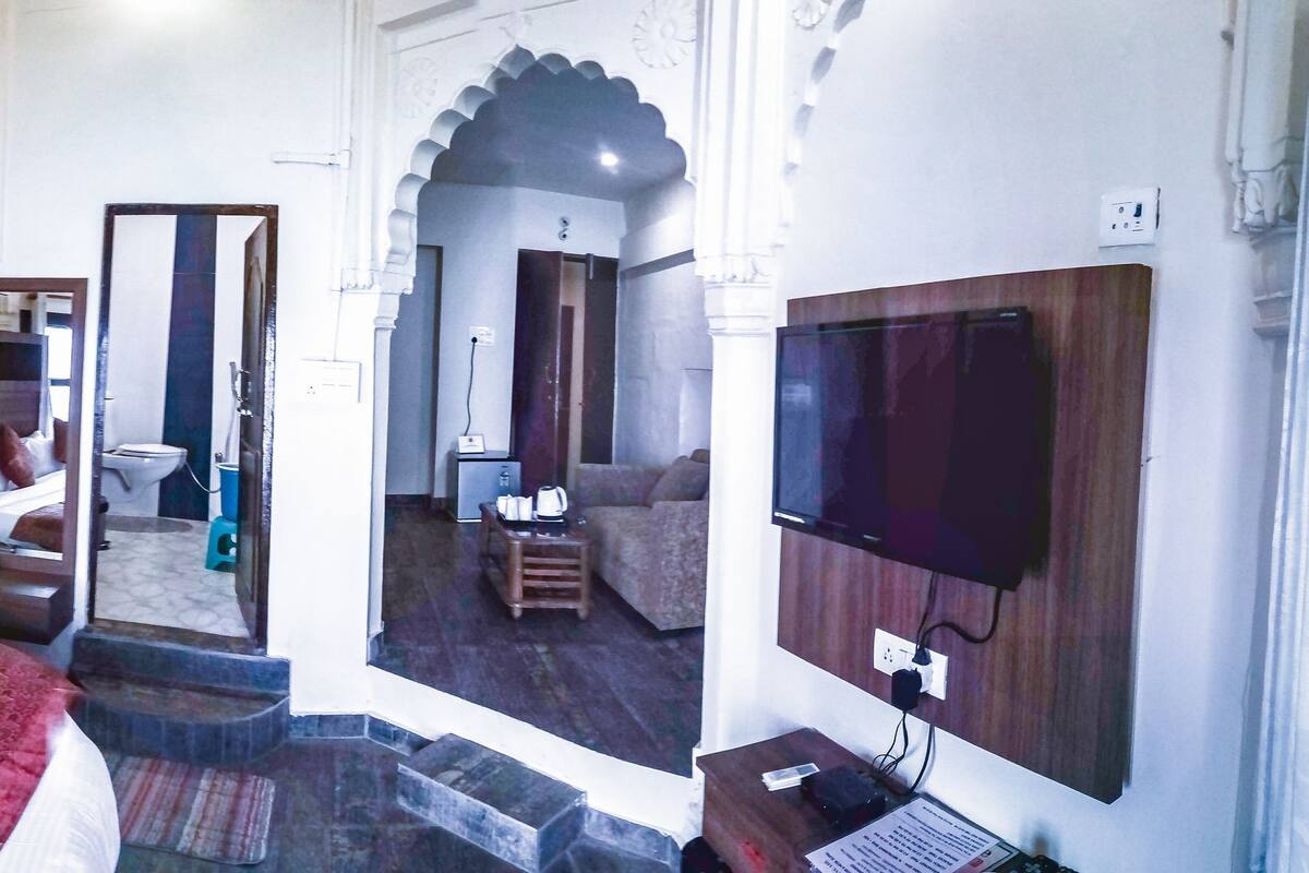 Una habitación tradicional con cama, televisor de pantalla plana y vista al baño.