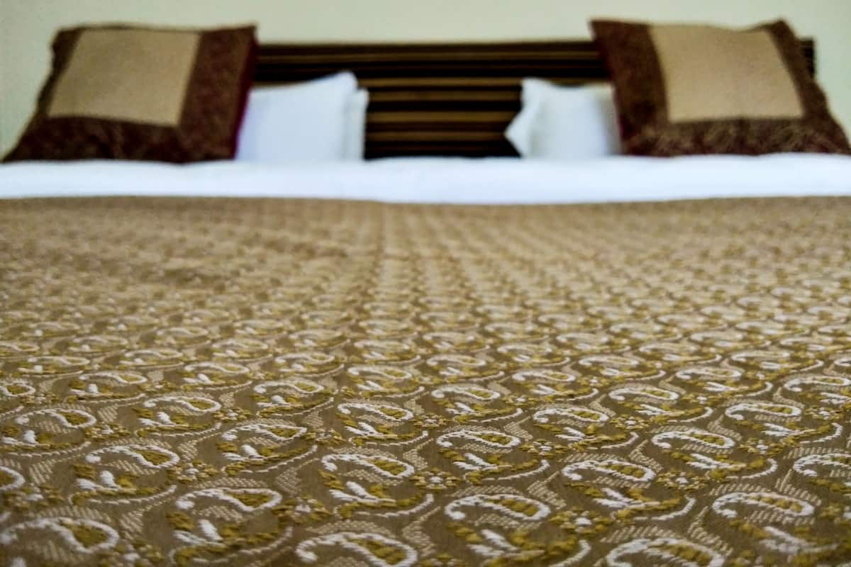 Una cama con una colcha estampada y dos almohadas.