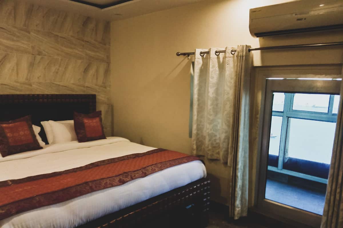Un dormitorio con una cama grande, cabecera y una ventana con cortinas.