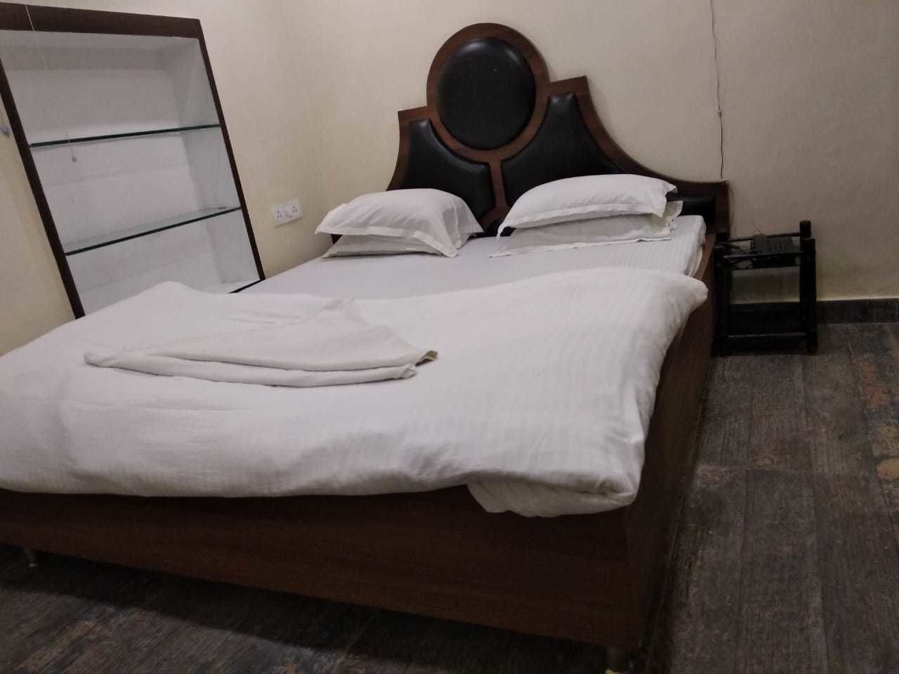 A neatly made bed with white linens and a wooden headboard.