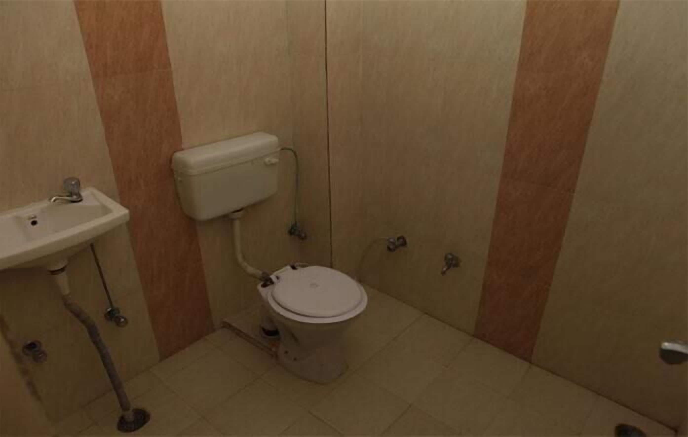 A small, compact bathroom with a toilet, sink, and storage cabinet.