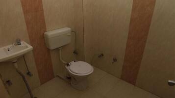A small, compact bathroom with a toilet, sink, and storage cabinet.