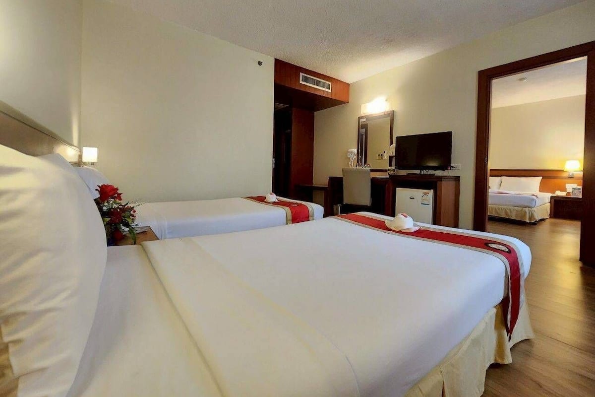 Ein Hotelzimmer mit zwei Betten, einem Schreibtisch, einem Fernseher und einem Badezimmer.