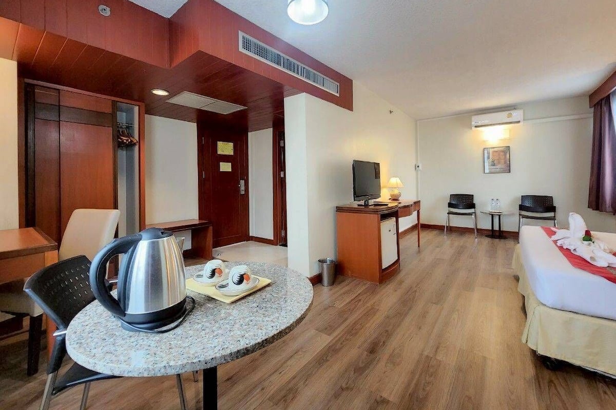 Ein Hotelzimmer mit Essbereich, Fernseher, Bett und Küchenzeile.