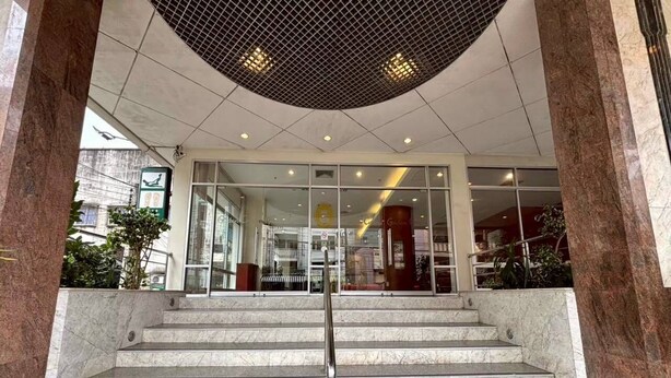 A set of marble stairs leading to a building entrance with glass doors and a metal handrail.