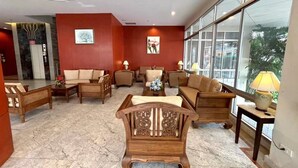 A lobby with multiple seating areas, a reception desk, and large windows offering a view of the outdoors.