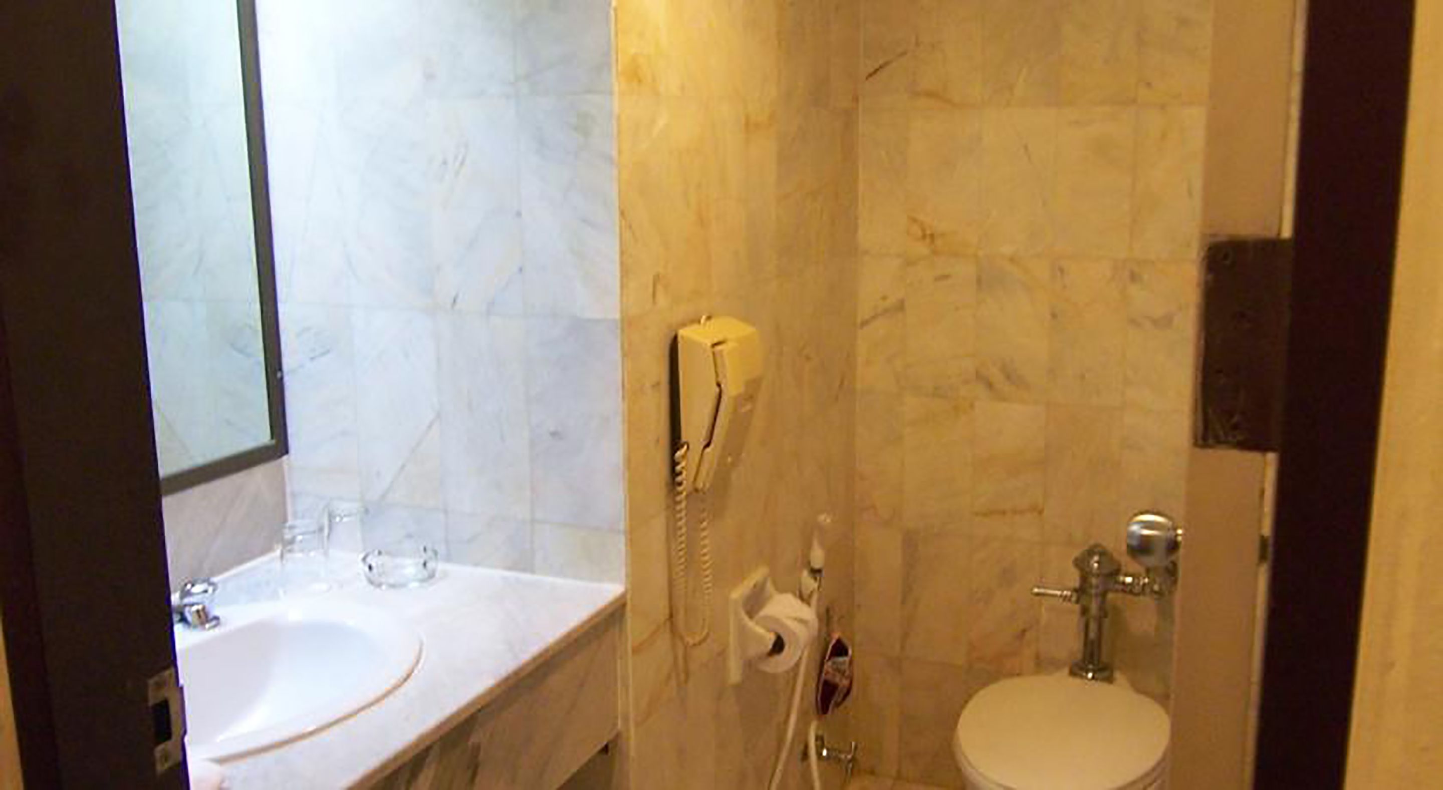 A bathroom with a sink, toilet, and a telephone.