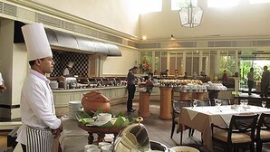A restaurant with a chef, a buffet area, and dining tables. - Hansa JB Hotel (Hat Yai)