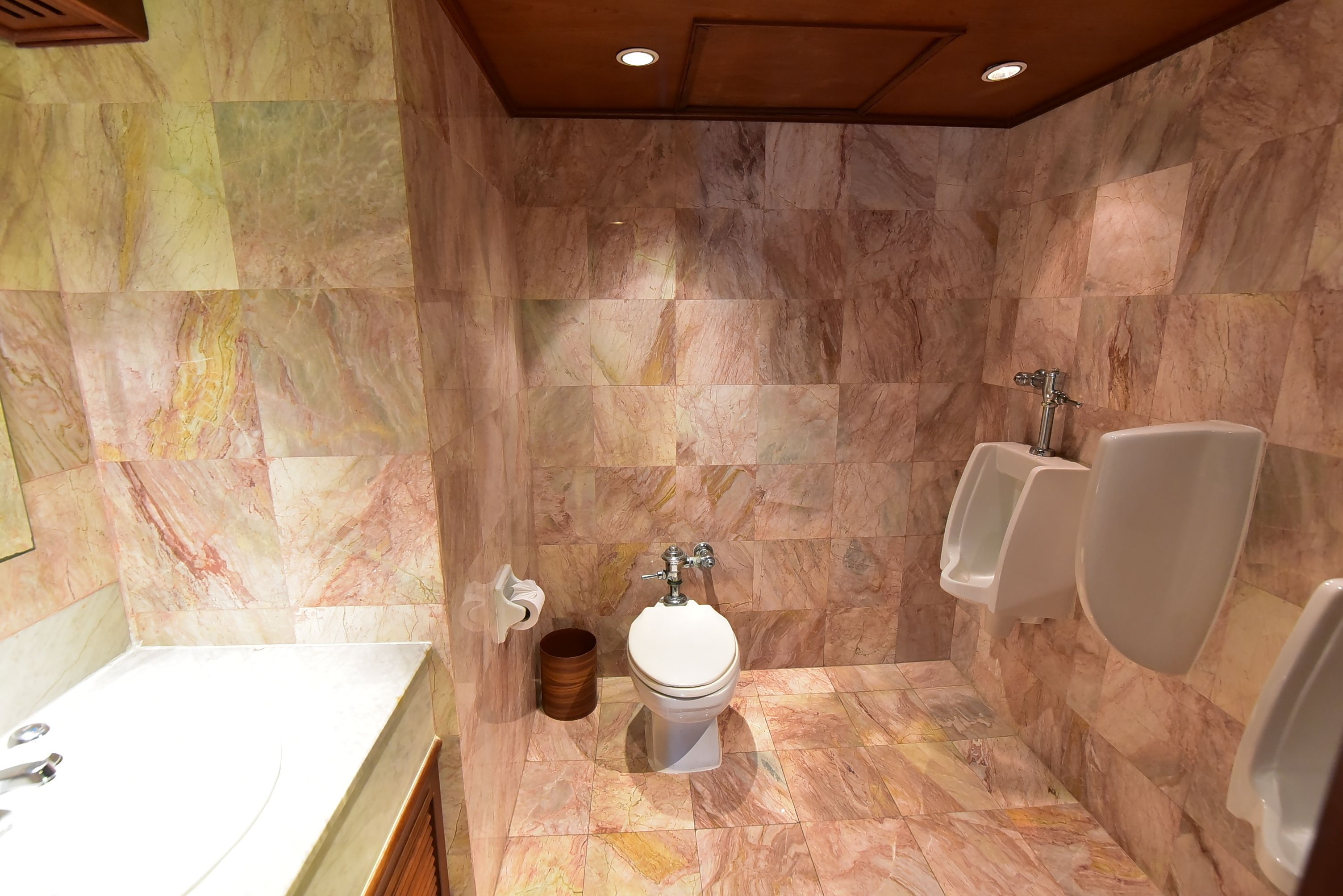 A bathroom with a marble floor, a toilet, urinals, and a sink.