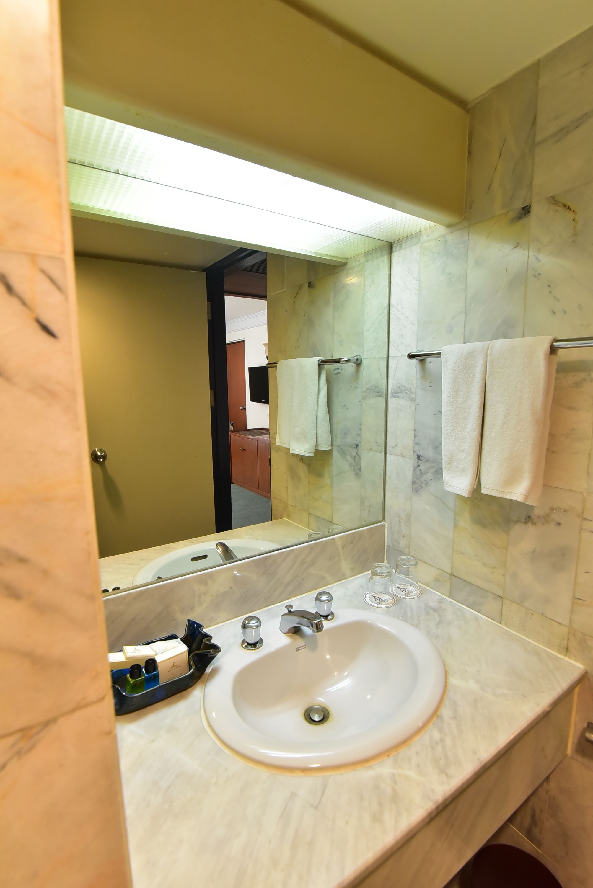 A bathroom with a marble sink, a large mirror, and a towel rack.