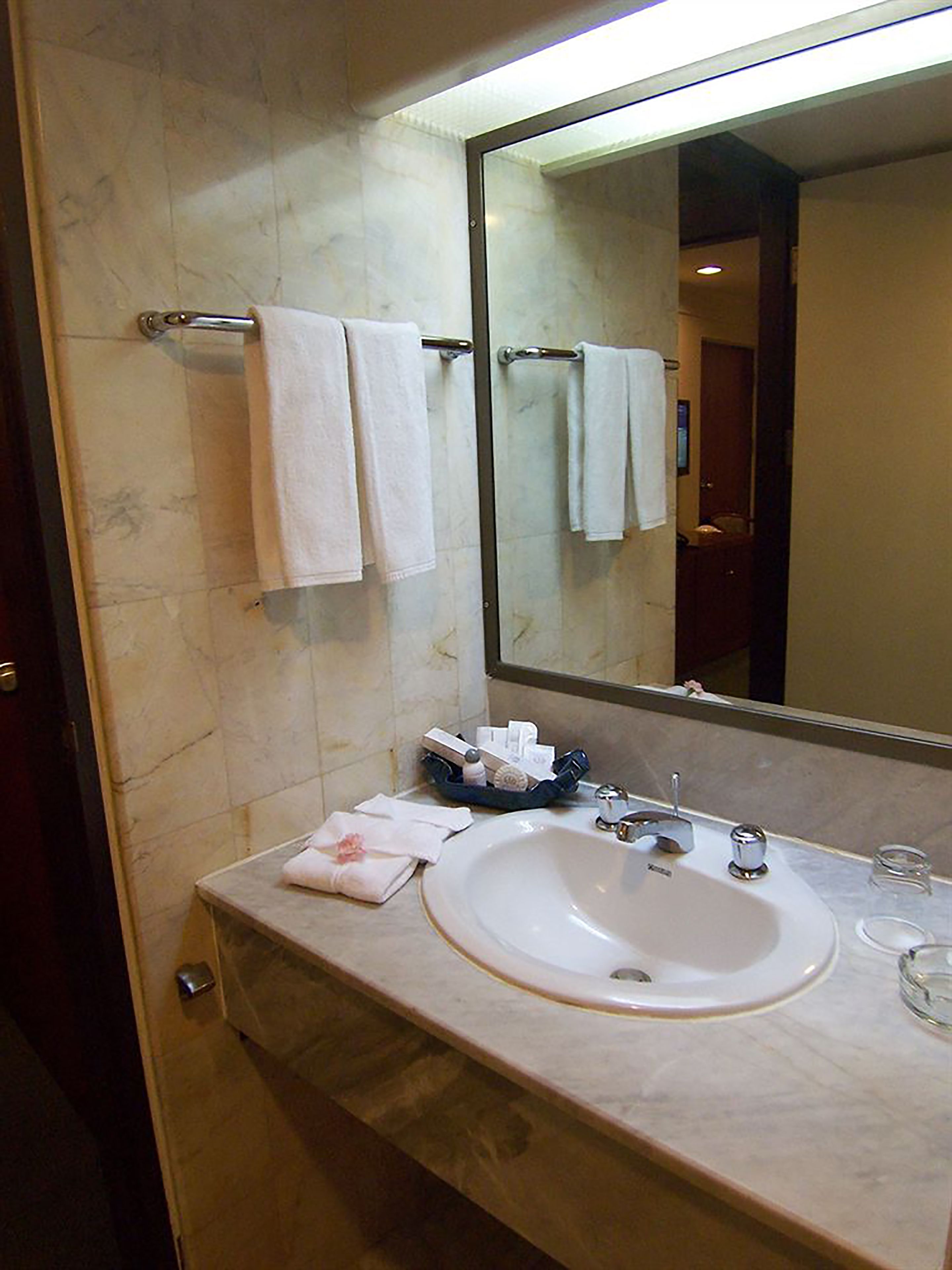 A bathroom with a marble sink, a mirror, and two towels hanging on a towel rack.