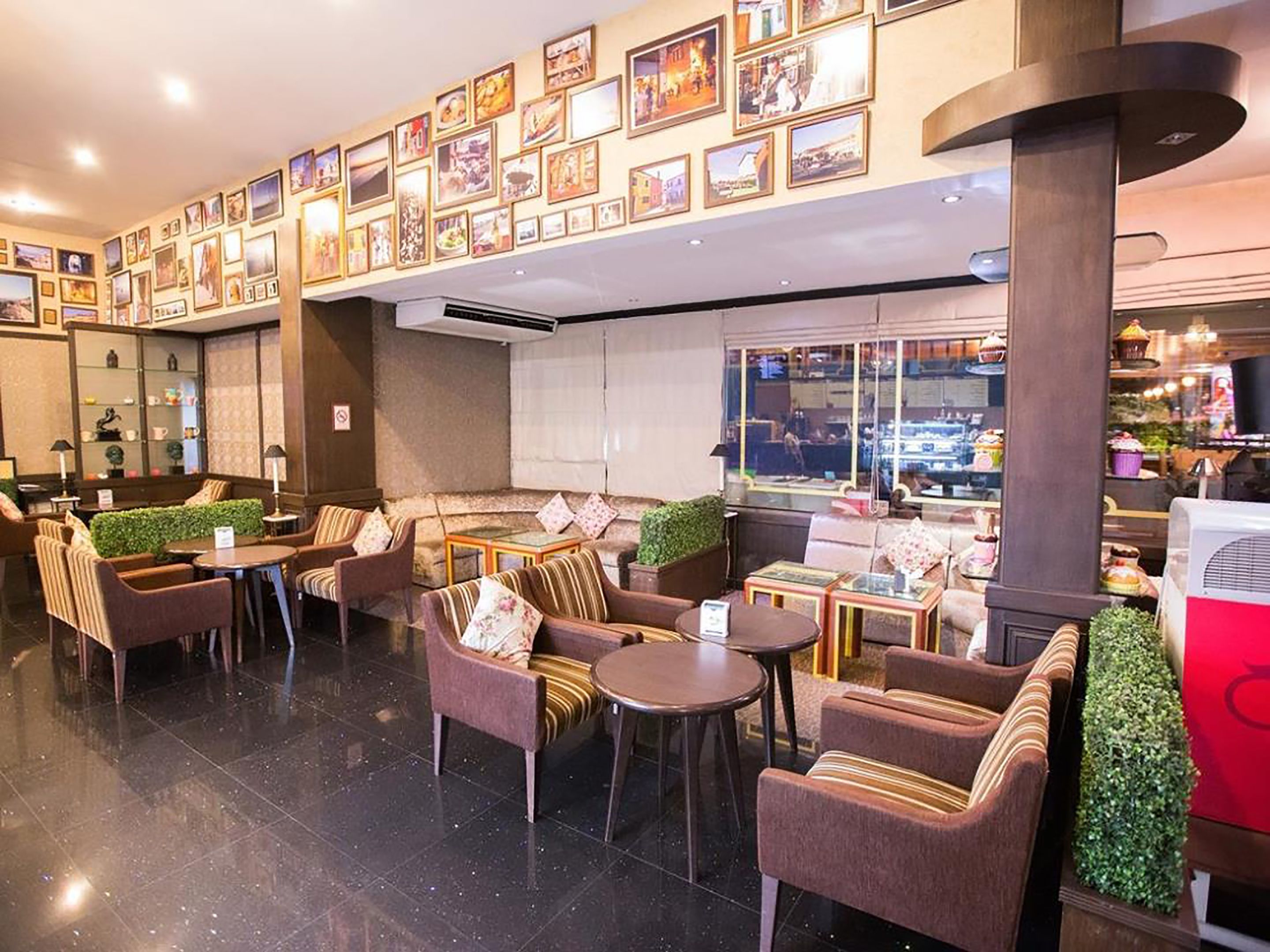 A hotel lobby with a seating area featuring sofas and chairs, a coffee bar, and a wall decorated with framed pictures.